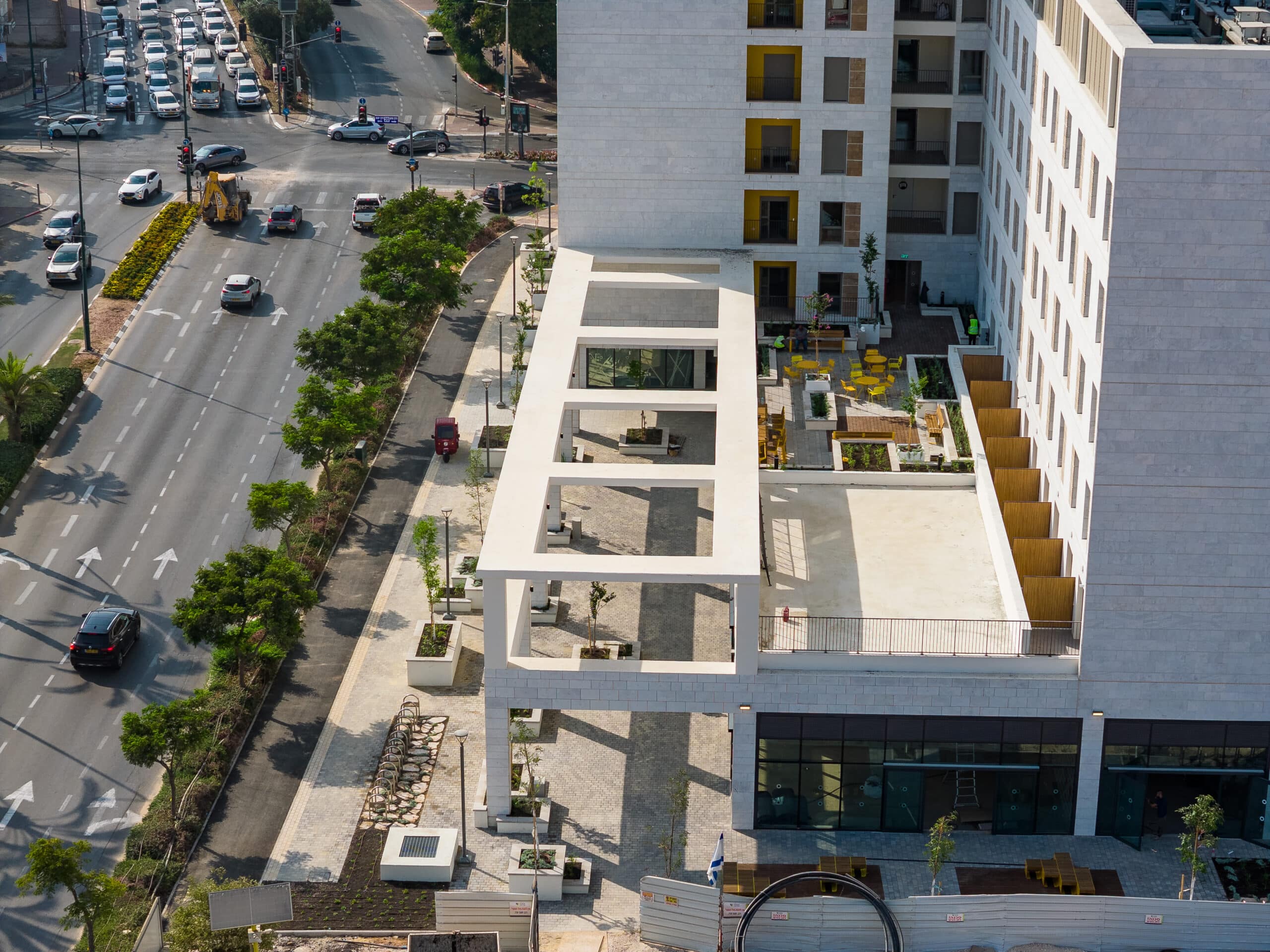 בניין עירוני גדול בצמוד לכביש סואן עם עצים וקרוסלת כביש."